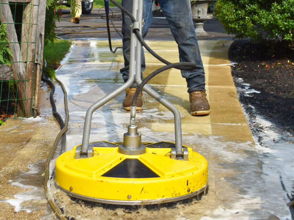 man pressure washing a sidewalk